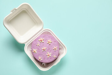 Obraz na płótnie Canvas Plastic lunch box with tasty bento cake on turquoise background