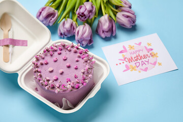 Plastic lunch box with tasty bento cake, greeting card and flowers on blue background