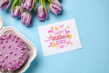 Plastic lunch box with tasty bento cake, greeting card and flowers on blue background