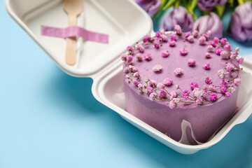 Plastic lunch box with tasty bento cake on blue background, closeup