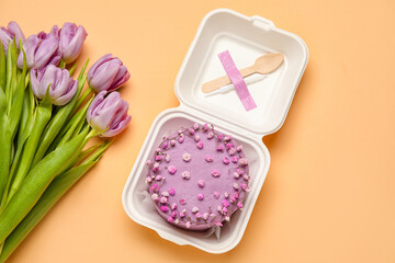 Plastic lunch box with tasty bento cake and flowers on orange background