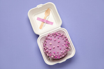 Obraz na płótnie Canvas Plastic lunch box with tasty bento cake on purple background