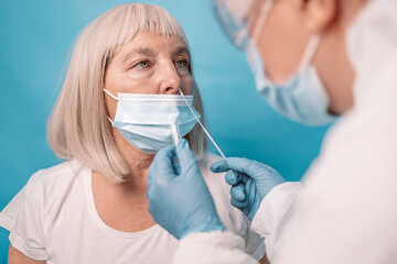 Close up of doctor in medical PPE suit takes sample from nose of a patient to Covid-19 rapid...