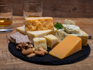 British drinks and food, glasses of Scotch whisky and cheeses collection, blue Stilton, Scottish coloured and English matured cheddar cheeses