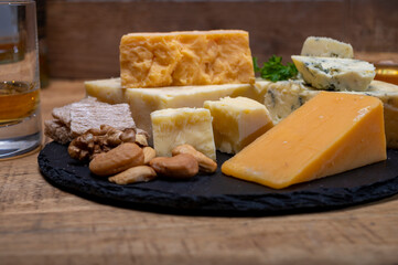 British drinks and food, glasses of Scotch whisky and cheeses collection, blue Stilton, Scottish coloured and English matured cheddar cheeses
