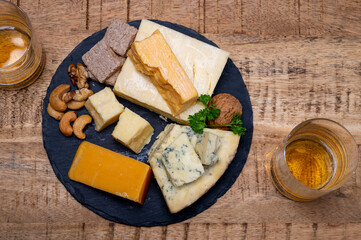 British drinks and food, glasses of Scotch whisky and cheeses collection, blue Stilton, Scottish coloured and English matured cheddar cheeses