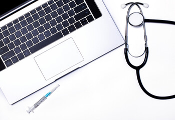 Laptop with keyboard, syringe and stethoscope on a light background. Modern medical information technologies and software. Diagnostics and repair of computers and gadgets. Copy space