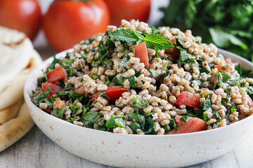 Tabbouleh salad. Traditional Levantine middle eastern or Arab dish for Iftar made with parsley, mint, bulgur and tomato.  Served with pita flatbread. Selective focus with blurred background.