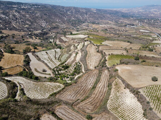 Aerial view on Troodos mountains, fertile valley with vineyards and olive groves and white roads,...