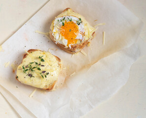 Sandwiches with cheese and scrambled eggs on parchment paper. Croc Monsieur and Croc Madame. Top view.