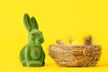Green Easter bunny and nest with eggs on yellow background