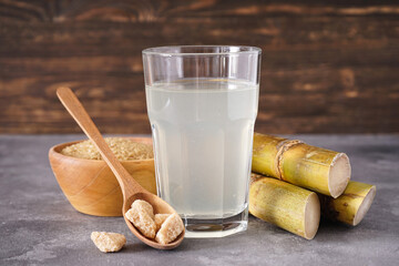Granulated brown sugar and fresh cane juice on a colour background.
