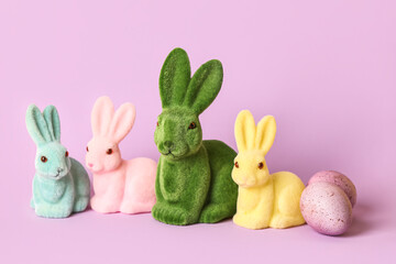 Different Easter bunnies and eggs on lilac background