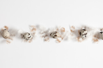 Easter background. Quail eggs and feathers on white background. Easter holiday concept. Flat lay, top view, copy space