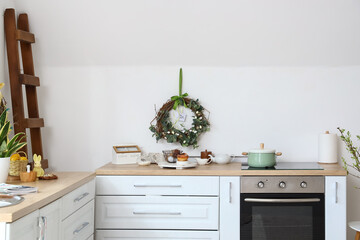 Different utensils on kitchen counter and Easter decor near white wall