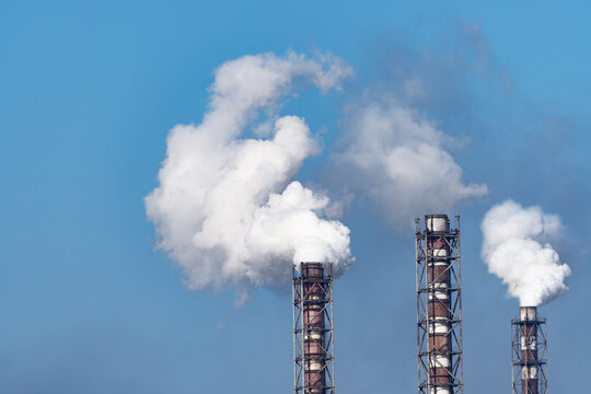 Smoke stack of coal power plant on blue sky background.