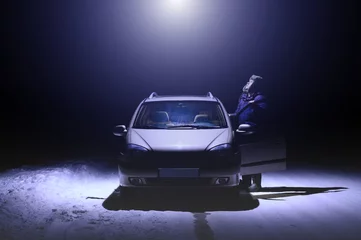 Outdoor kussens De man staat naast de auto en kijkt omhoog naar de lichtstraal die uit de UFO komt. Donkere winternacht. Gekleurd in trendkleur Very Peri © Ramil Gibadullin