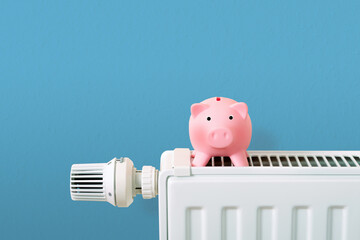 save heating costs, pink piggy bank  on radiator, blue background