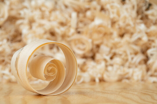 wood shavings close-up on a wooden table against the background of other shavings and sawdust.