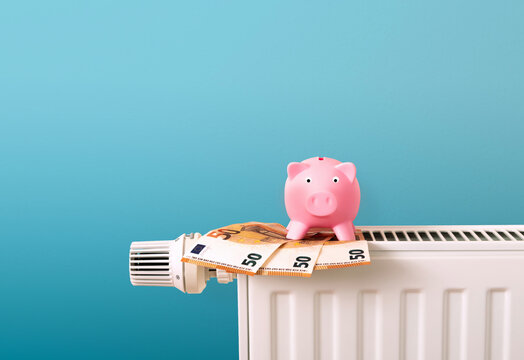 save energy and heating costs in winter, piggy bank on radiator and money notes