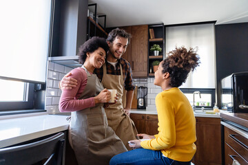 Portrait of happy multiethnic family with child in kitchen having fun and breakfast