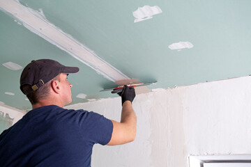 Worker applying putty on drywall