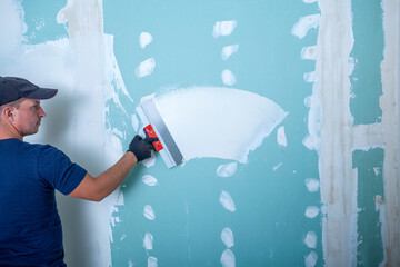Hand of builder worker plastering at wall