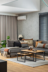 Fototapeta na wymiar Creative composition of elegant living room interior with grey corner sofa, coffee table and stylish personal accessories. Modern home decor. Panoramic windows. Template.