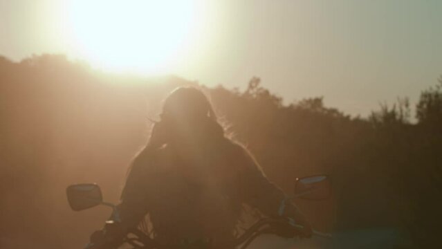Biker girl riding a motorcycle bike in the sunset