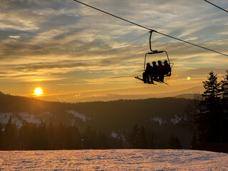 skiers on the chairlift during sunset
