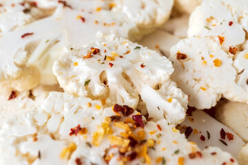 Raw slices of cauliflower sprinkled with spices. Cooking cauliflower steak.