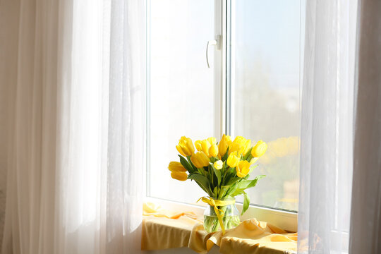 Glass vase of yellow tulips on windowsill