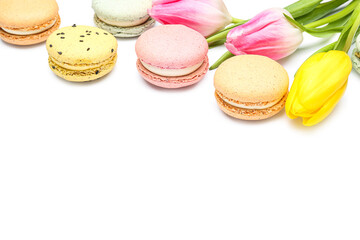 Sweet macaroons with tulip flowers on white background, closeup. International Women's Day celebration
