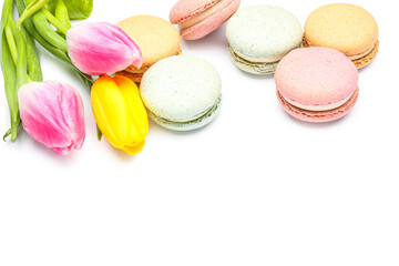 Tasty macaroons and beautiful tulip flowers on white background, closeup. International Women's Day celebration