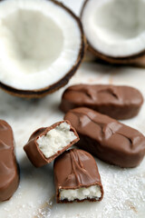 Delicious milk chocolate candy bars with coconut filling on white table, closeup
