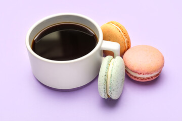 Cup of coffee and sweet macaroons on lilac background