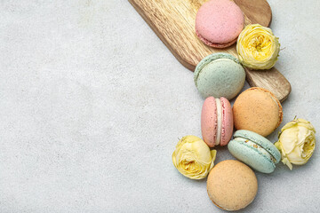 Tasty macaroons and beautiful rose flowers on light background. International Women's Day celebration