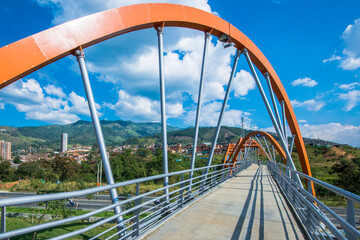 Obraz na płótnie Canvas Pedestrian bridge with beautiful landscape and blue sky. Bello, Antioquia, Colombia.