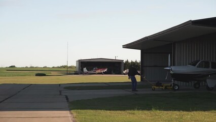 Man Pulling Small Aircraft out of Hangar - Powered by Adobe