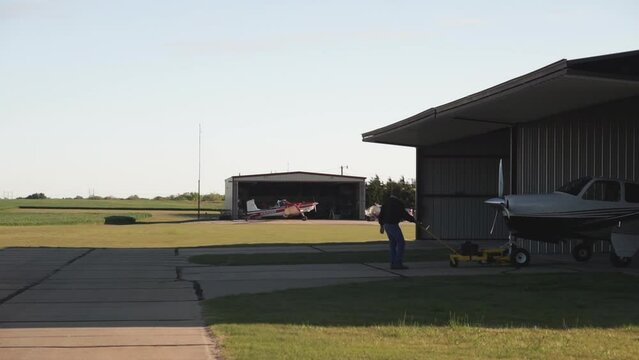 Man Pulling Small Aircraft out of Hangar
