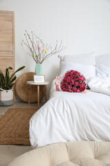 Bouquet of flowers, Easter bunny and eggs on soft bed in light room