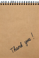Thank you inscription written with a marker on brown paper in a notepad. Gratitude in the form of an inscription thank you with free space for text or advertising on brown paper