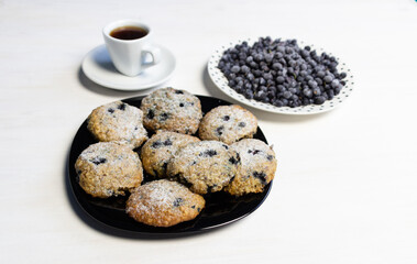 heap of frozen blackberry, cup of coffee and blueberry cookies on white table