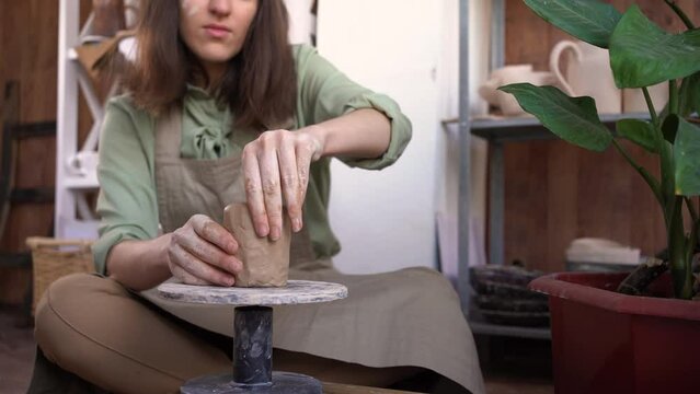 female potter sculpts a piece of clay at a table. A woman makes a ceramic object. Pottery, handicraft and creative skills in an art studio. hands of the master close-up.