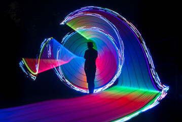 One person standing alone against beautiful color circle LED light painting as the backdrop	