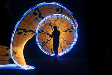 One person standing alone against beautiful color circle LED light painting as the backdrop	