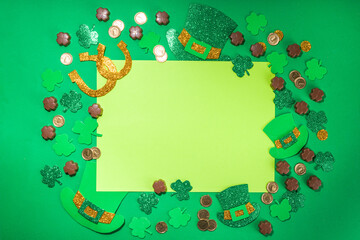 St Patrick flatlay background with shamrock clover leaves, leprechaun hat decor, golden coins and...