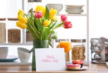 Vase with flowers, breakfast and greeting card with text HAPPY WOMEN'S DAY on kitchen counter