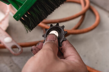 A repairman or technician uses a brush to scrub a dirty derailleur pulley cog of a mountain bike. Maintenance service at a bicycle repair shop.