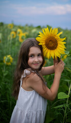 beautiful girl stands in a field with sunflowers